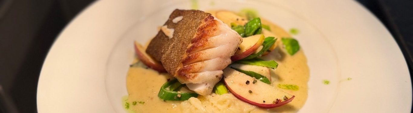 Restaurant – Fischgericht Gebratenes Fischfilet mit Gemüse und Sauce auf einem weißen Teller